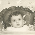 Carole Lee 1940 in her high chair with bo peep wall paper behind