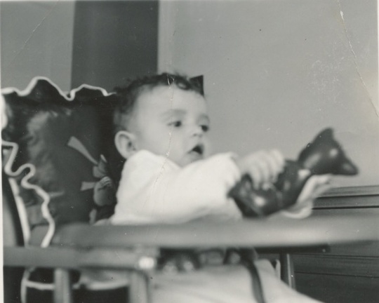 Carole Lee in her fancy high chair about 1-2 months playing with a toy